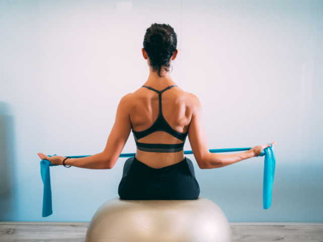 Young sporty attractive woman practicing pilates with resistance